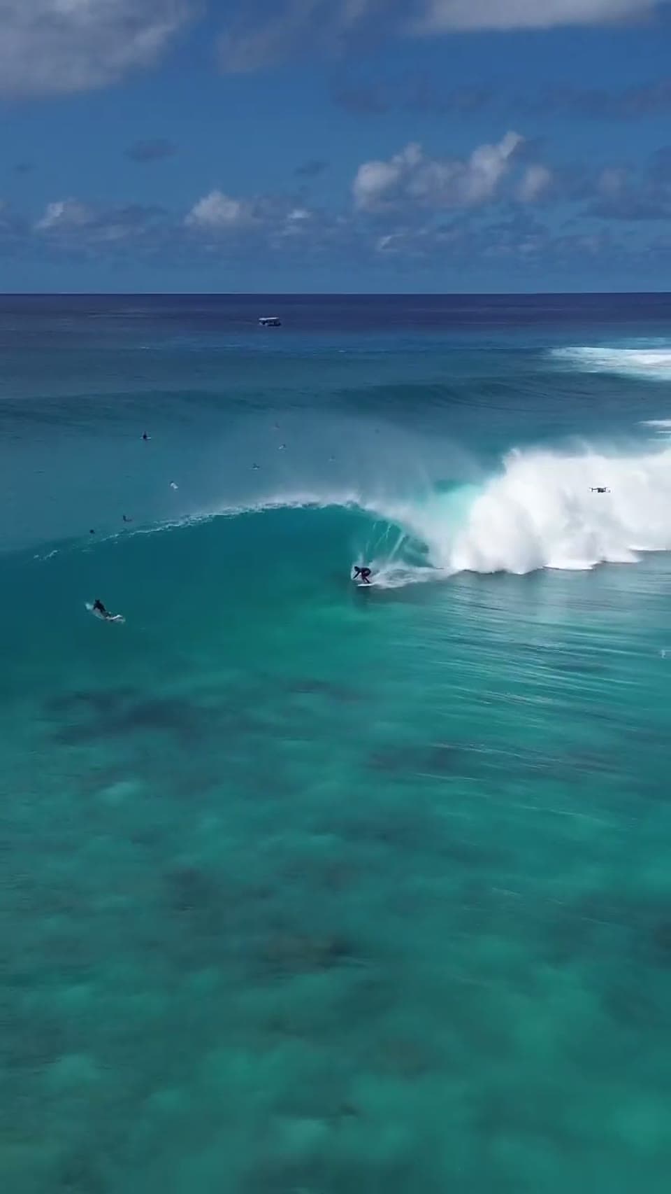 A surfer taking a line along a turquoise reef wave