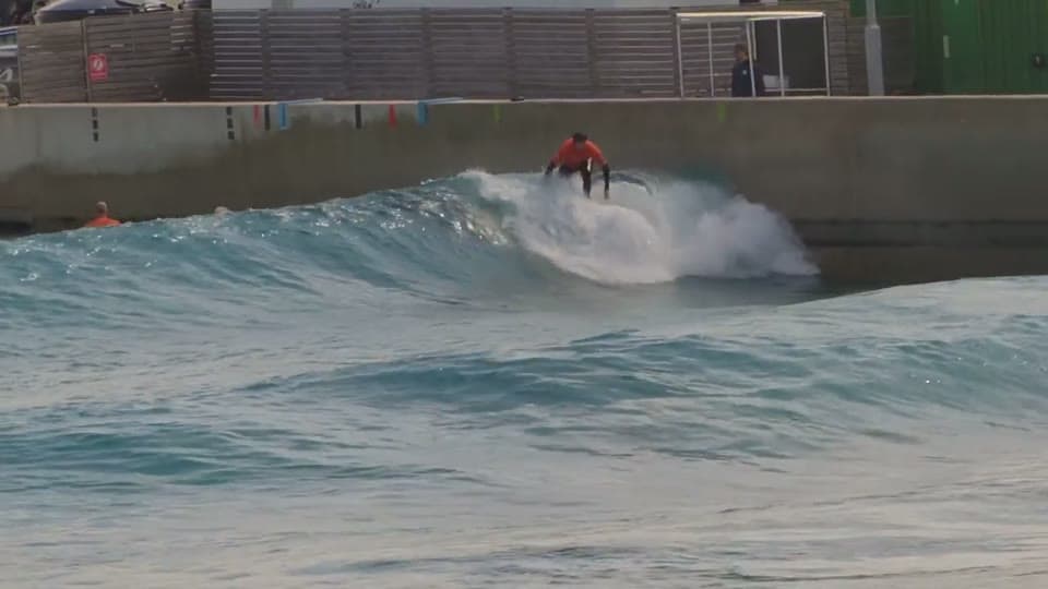 Surfer riding a breaking wave at a surf pool