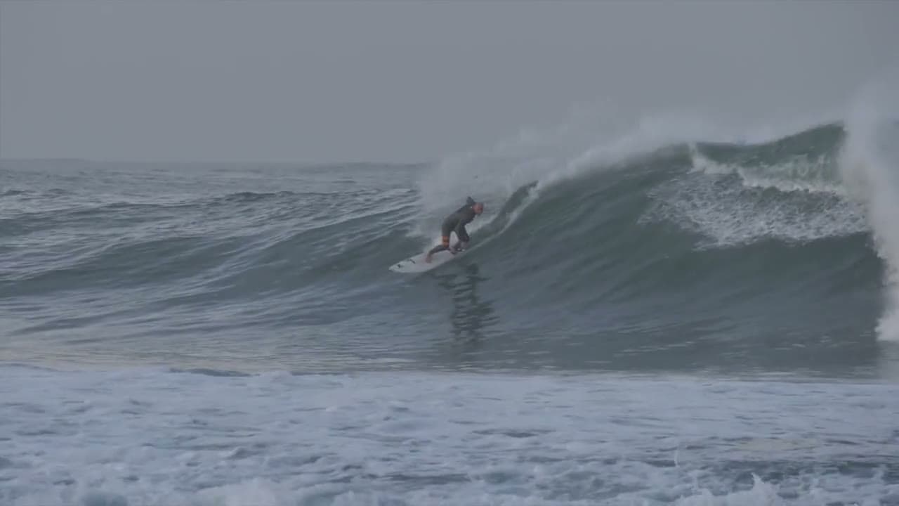 Surfer setting a line beneath the lip of a large ocean wave